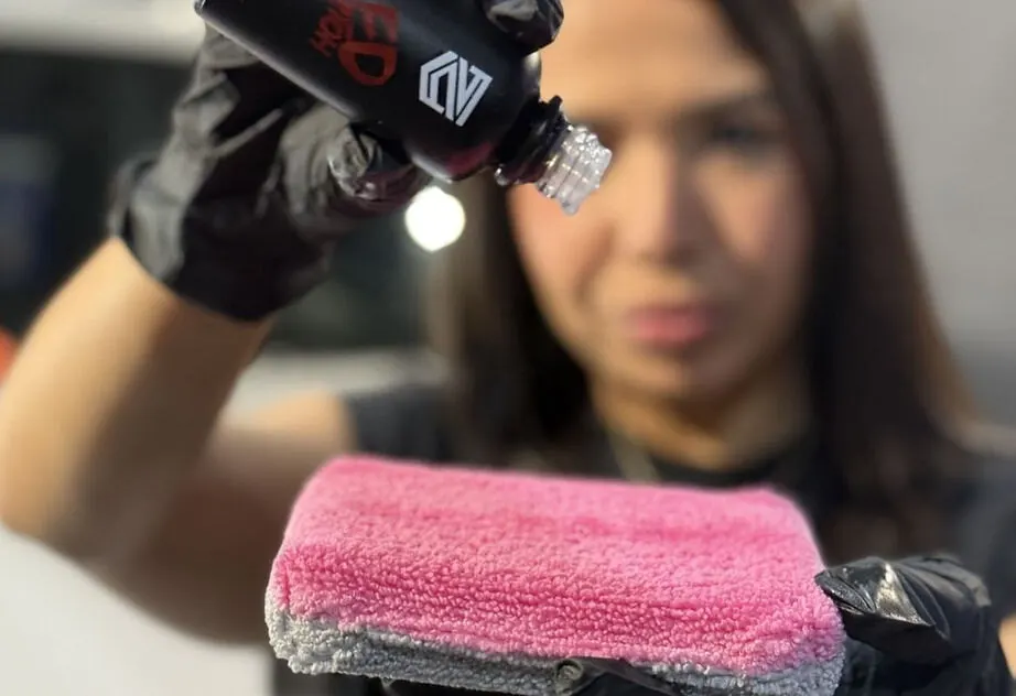 Close-up of ceramic coating being applied to a car panel with a pink applicator pad