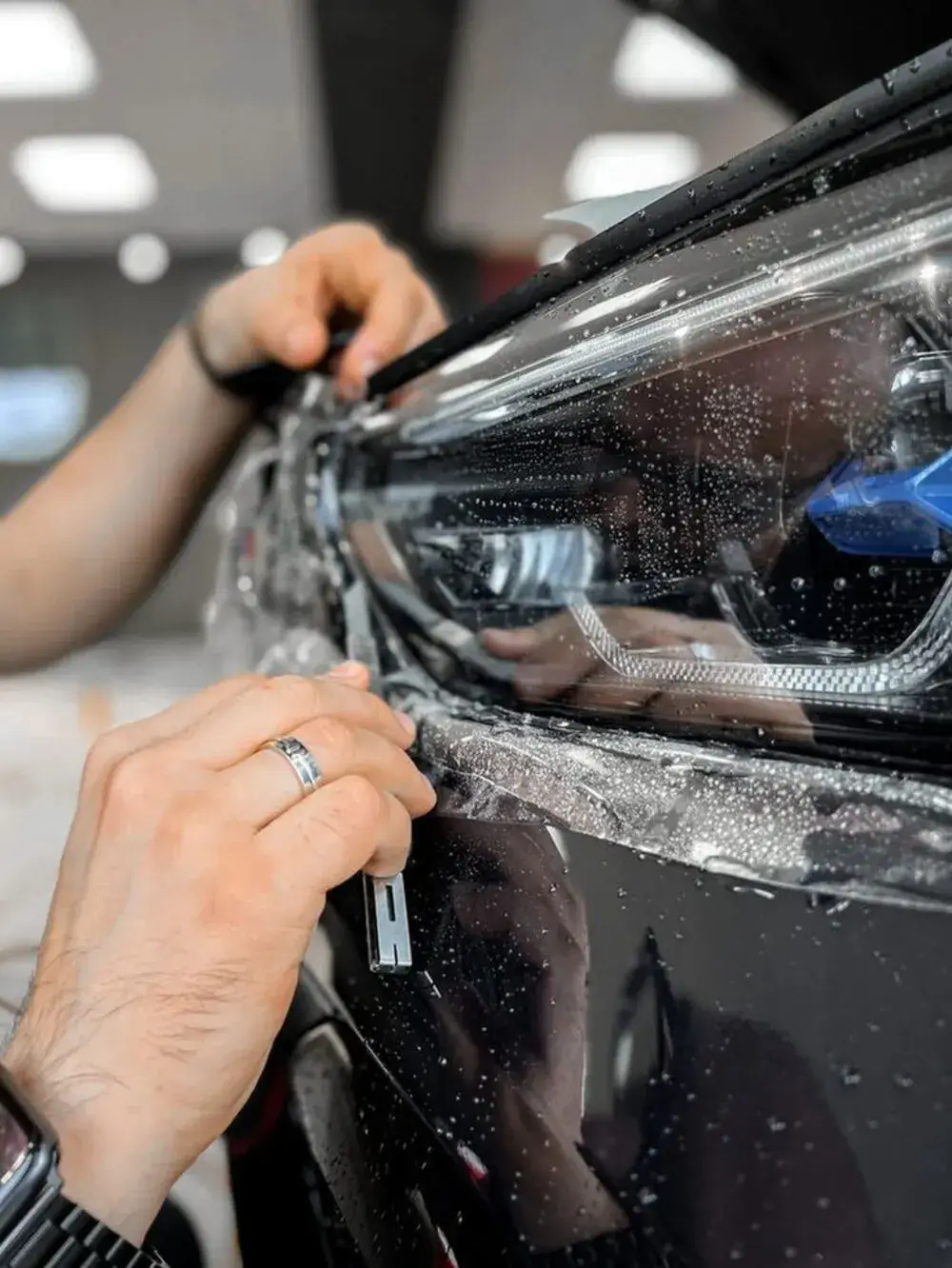Seamless paint protection film edge tucked under a car headlight